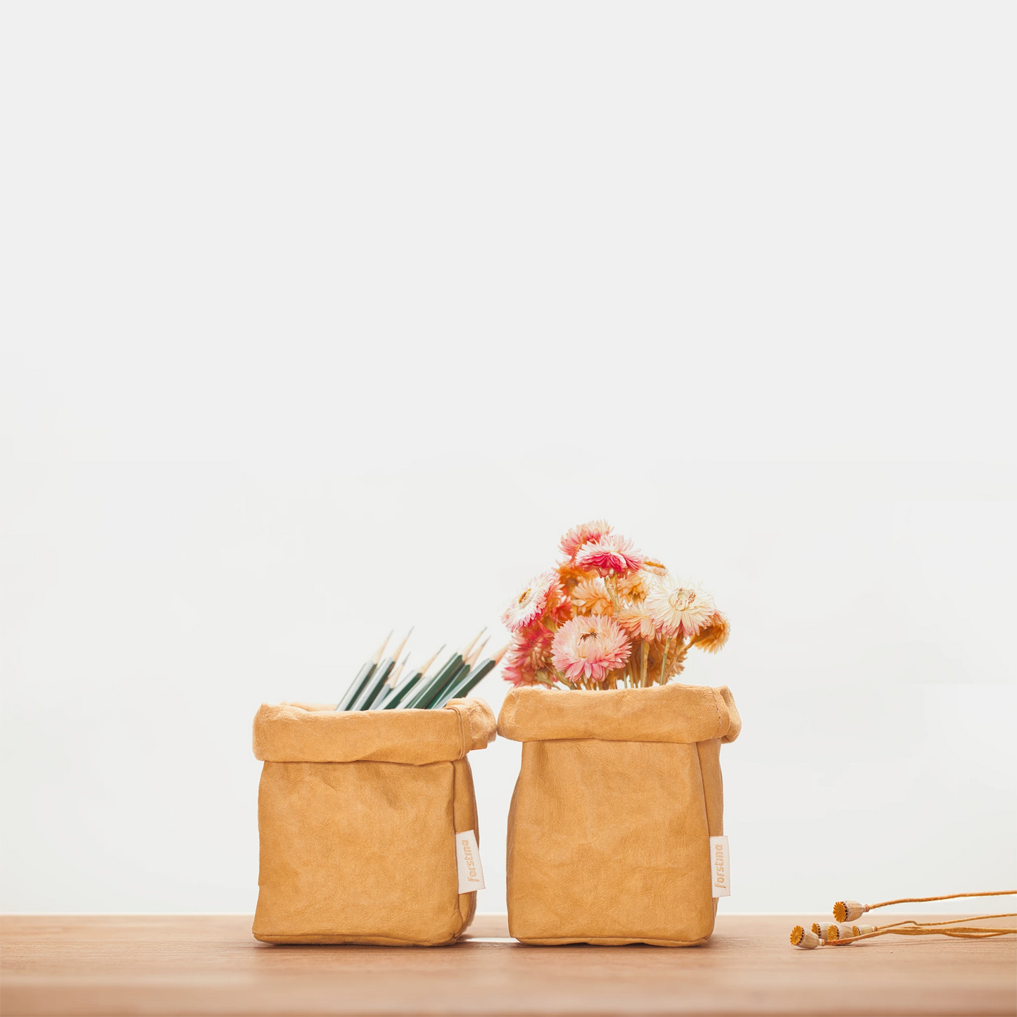 Two environmentally friendly forstina washable kraft paper bags are put together, one with pencil and the other with golden flowers.